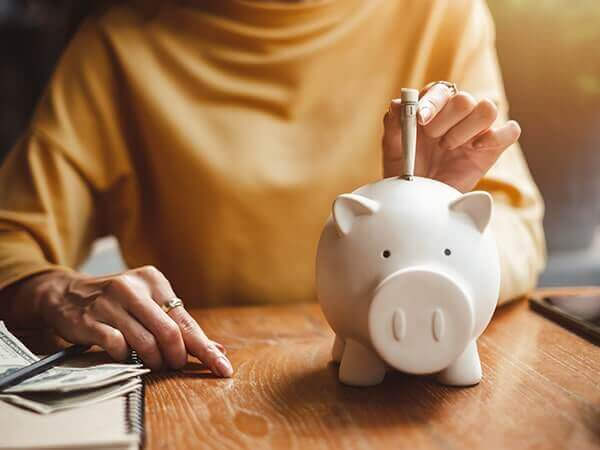 person adding money to piggy bank