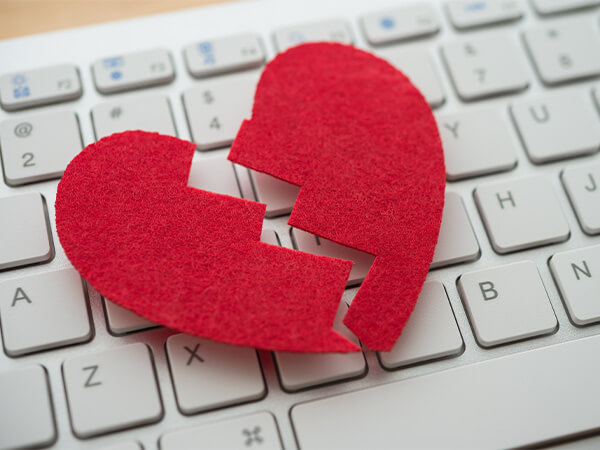Red, broken heart over white computer keyboard