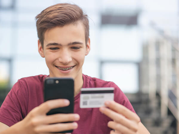 Teen looking at card and paying over phone