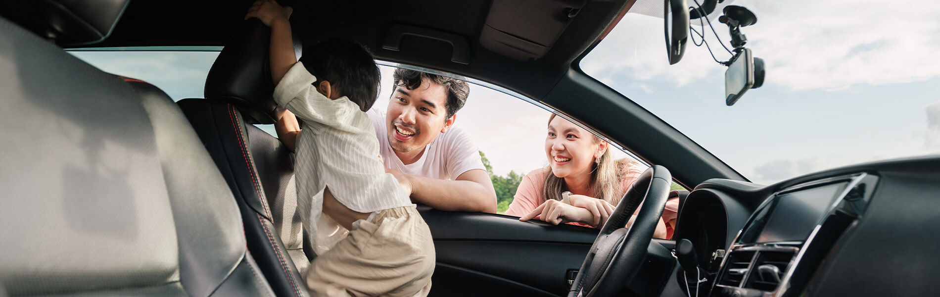 Young family with infant looking inside their new car
