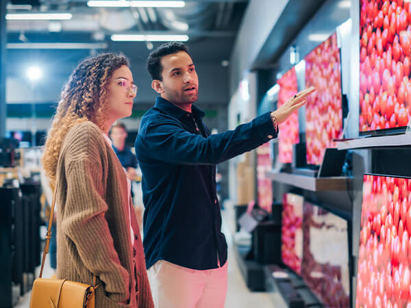 Woman looking at new televisions with salesperson
