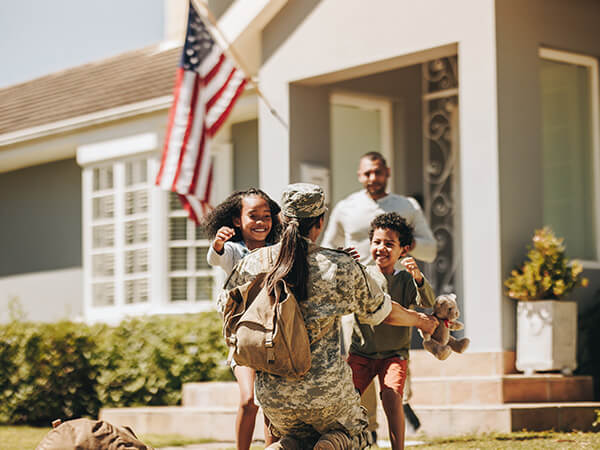 Military woman getting welcomed by her young kids and husband