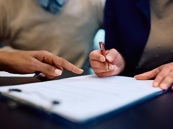 Close-up of two people signing paperwork